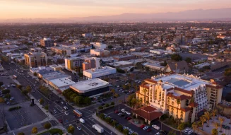 Aerial view of residential and commercial buildings in Downey California during a warm sunset with mountains in the background tg renovations