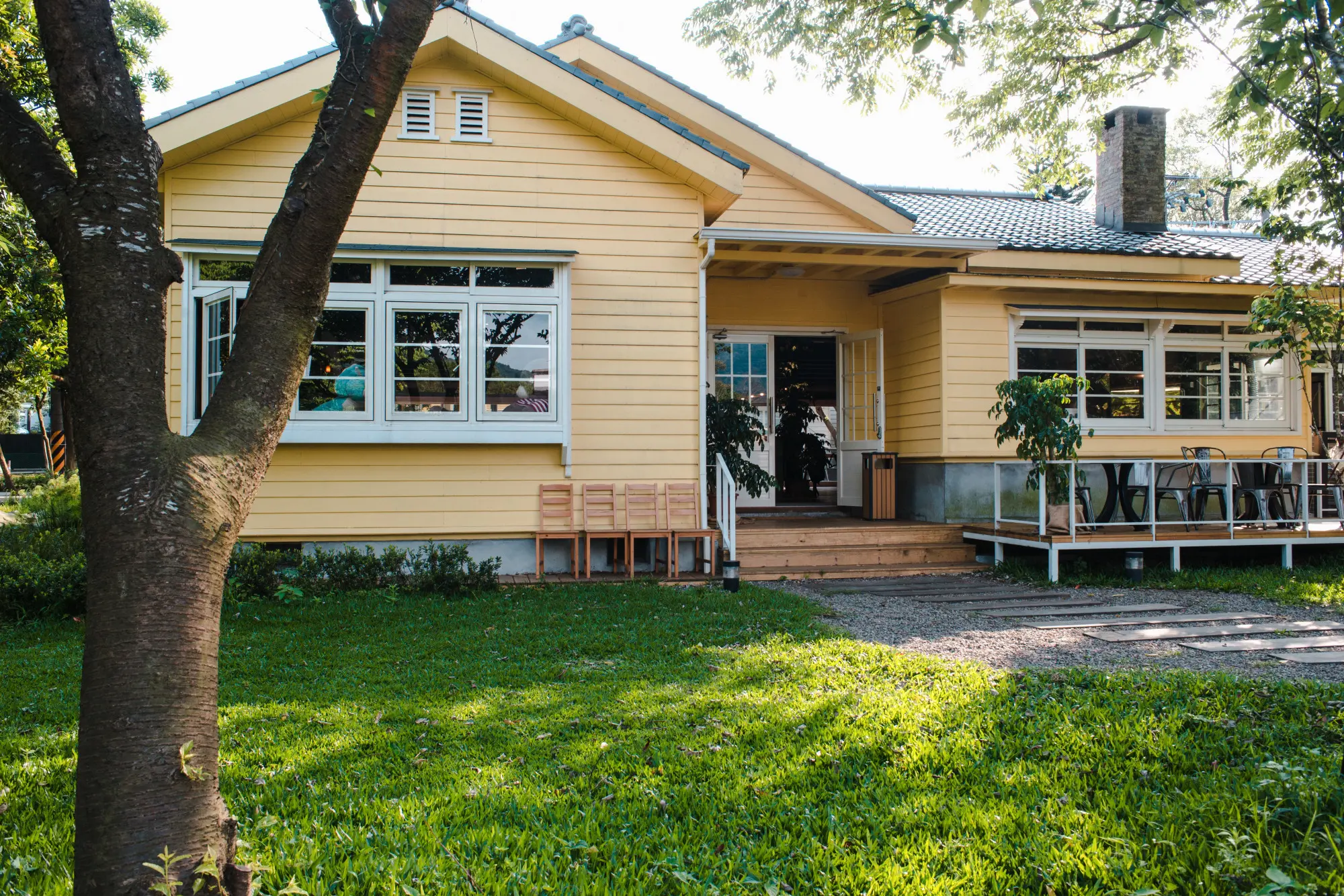 Charming yellow craftsman-style home with horizontal siding and a wooden porch, representing an owner-builder ADU in California – TG Renovations